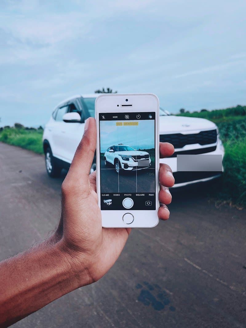 Telefonla beyaz bir SUV’un fotoğrafını çeken el